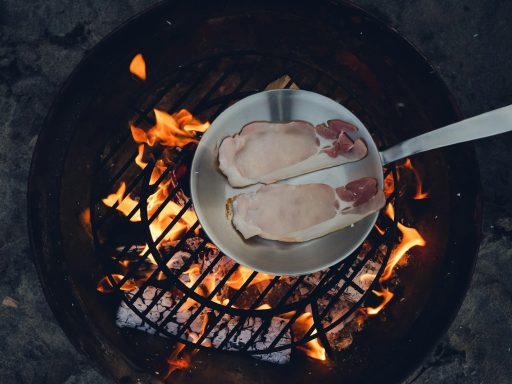 person cooking steak on charcoal gril