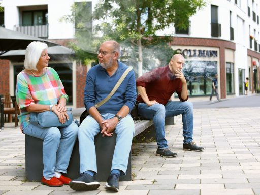 three people sitting on a bench talking to each other