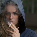 woman wearing hoodie while holding cigarette