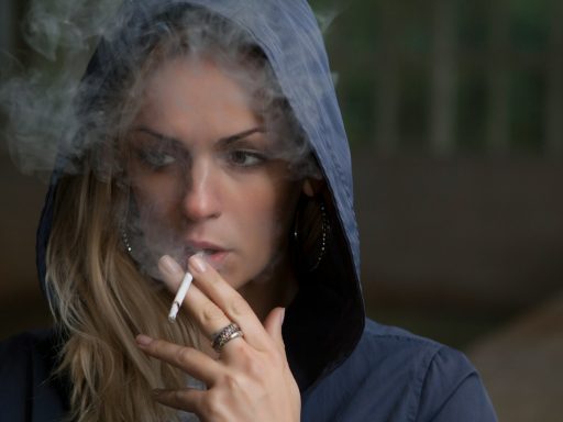 woman wearing hoodie while holding cigarette