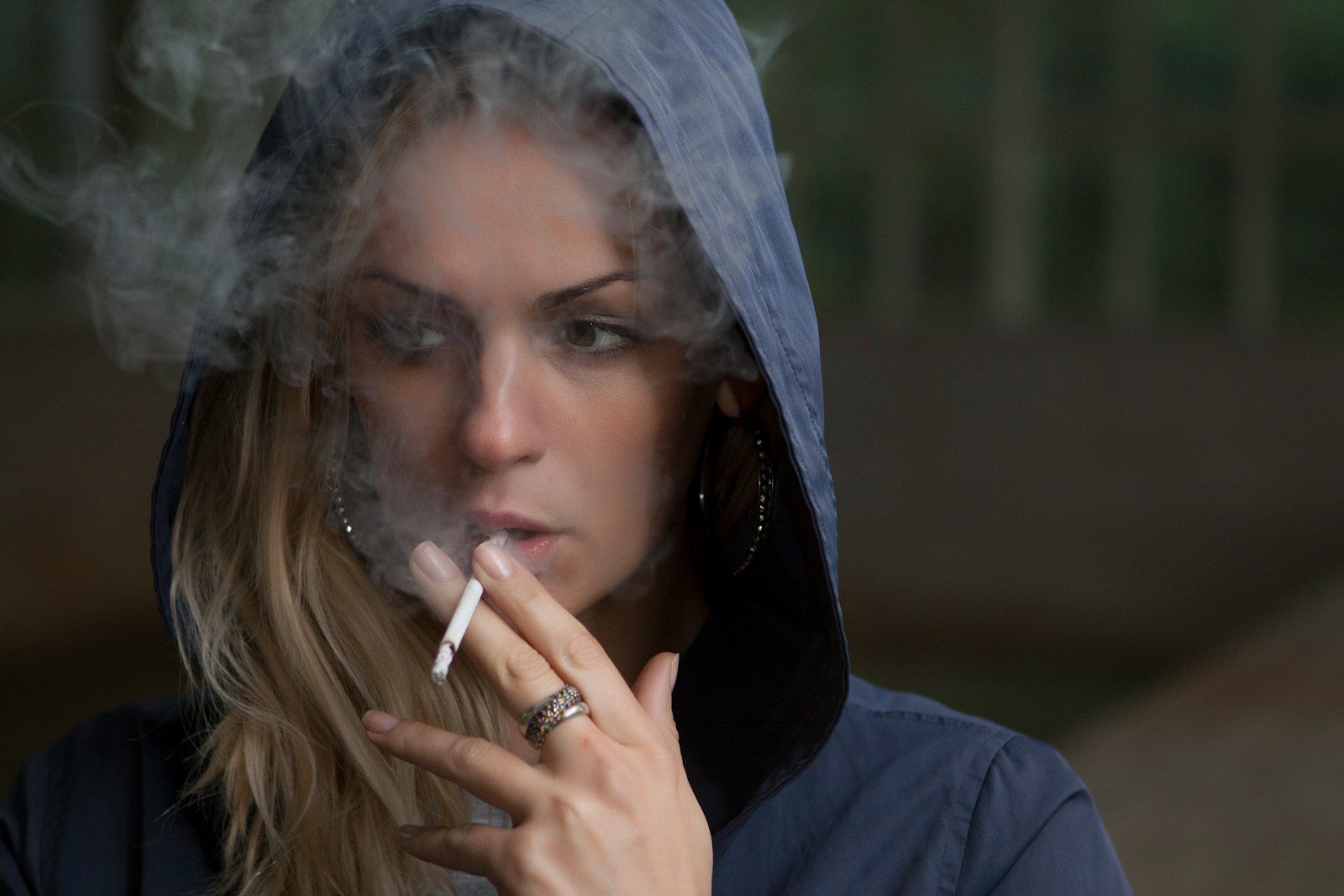 woman wearing hoodie while holding cigarette