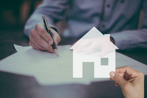 Huizensleutels naast een koopcontract op een bureau